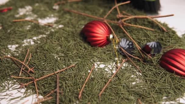 Yakın plan çekimde, bir adam kırık Noel topları ve yerden düşen çam iğneleriyle kuru çam dalları topluyor. Gri bir kepçe ve yeşil bir fırça kullanıyor.. — Stok video