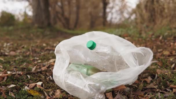 Ekolojik kavram plastiği durdurur. Çimlerin üzerinde plastik şişeler olan beyaz bir çanta. Plastik ile çevre kirliliği. — Stok video