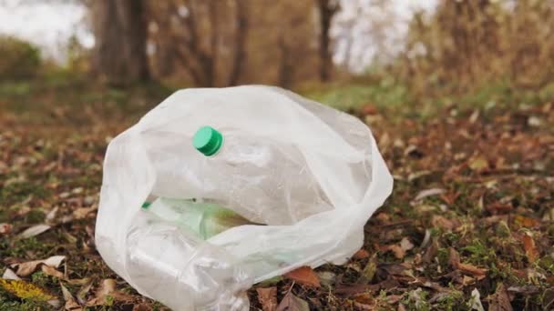 Ekolojik kavram plastiği durdurur. Çimlerin üzerinde plastik şişeler olan beyaz bir çanta. Plastik ile çevre kirliliği. — Stok video