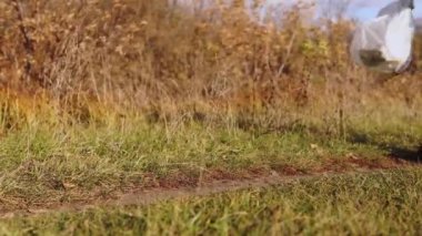 Ekolojik konsept plastik kirliliği. Kot pantolonlu sorumsuz bir adam doğada plastik şişelerle dolu bir çanta fırlatıyor..