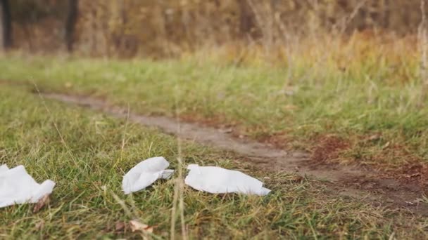 Concepto ecológico de recolección de basura. Un joven responsable recoge toallitas húmedas dispersas del suelo en la naturaleza, de cerca . — Vídeo de stock