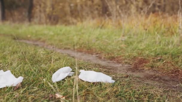 Екологічна концепція збору сміття. Відповідальний молодий чоловік підбирає розкидані вологі серветки з землі на природі, крупним планом . — стокове відео