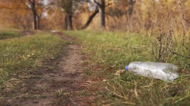 Οικολογική έννοια της συλλογής απορριμμάτων. Υπεύθυνος νεαρός άνδρας σηκώνει ένα πλαστικό μπουκάλι από το έδαφος στη φύση, κοντινό πλάνο. — Αρχείο Βίντεο