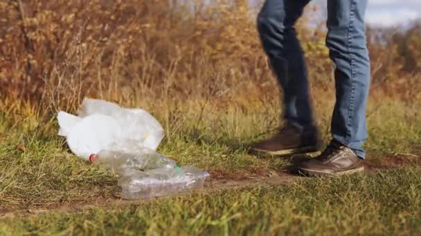 Ecologisch concept van afvalinzameling. Een verantwoordelijke jongeman pakt een verspreide zak met afval van de grond op van de natuur, close-up. — Stockvideo