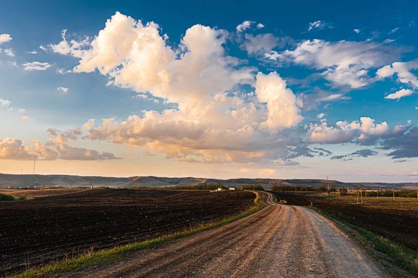 Сільська ландшафтна брудна дорога в полі і красиві хмари на заході сонця . — стокове фото