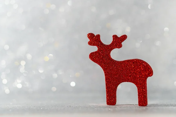Dekorative Weihnachtsfigur Hirsch auf silbernem Bokeh-Hintergrund. die Leerstelle links. Stockbild