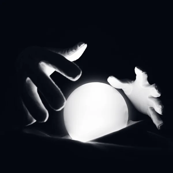 Sesión espiritual prediciendo el futuro. Manos abiertas con guantes blancos sobre una bola de cristal luminosa . — Foto de Stock