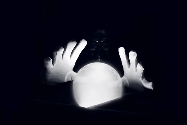 Sesión espiritual prediciendo el futuro. Manos abiertas con guantes blancos sobre una bola de cristal luminosa . — Foto de Stock