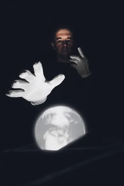 Человек-ясновидец держит руки в белых перчатках над волшебным хрустальным шаром. Сессия для будущего . — стоковое фото