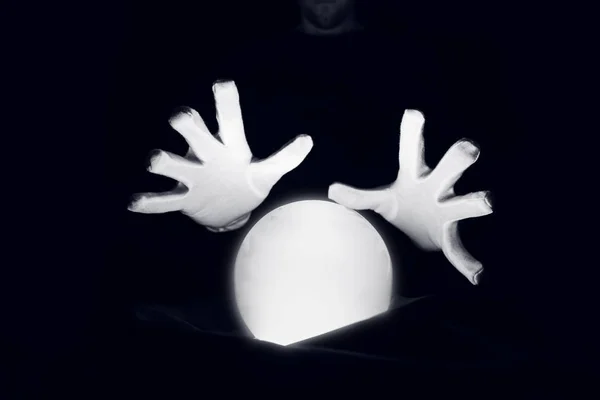 Spirituelle Sitzung, die die Zukunft voraussagt. Offene Hände in weißen Handschuhen über einer leuchtenden Kristallkugel. — Stockfoto