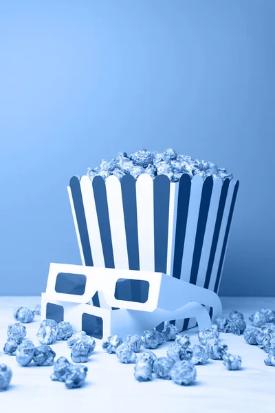Concept de cinéma de lunettes 3D et des collations éparpillant près de tasse en papier sur le tableau blanc sur le fond gris. Tonalité dans la couleur tendance 2020 bleu classique . — Photo