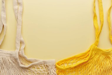 Two reusable mesh product bags on a yellow table.