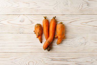 Hafif ahşap bir masada çirkin havuçlar.