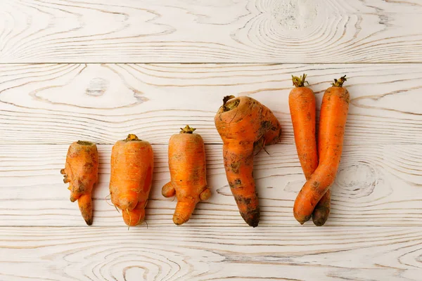 Ugly carrots on a light wooden table. — Stock Photo, Image