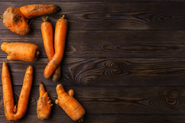 Koyu tahta bir masada çirkin havuçlar..