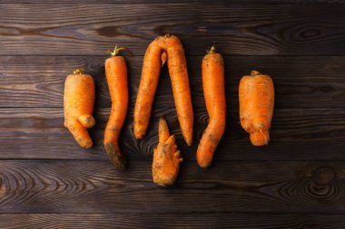 Koyu tahta bir masada çirkin havuçlar..