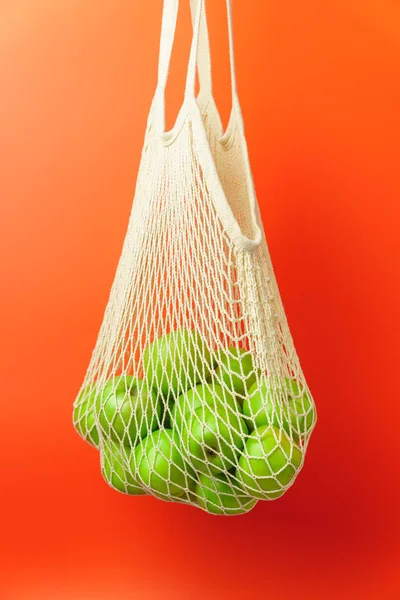 White string bag with green apples.