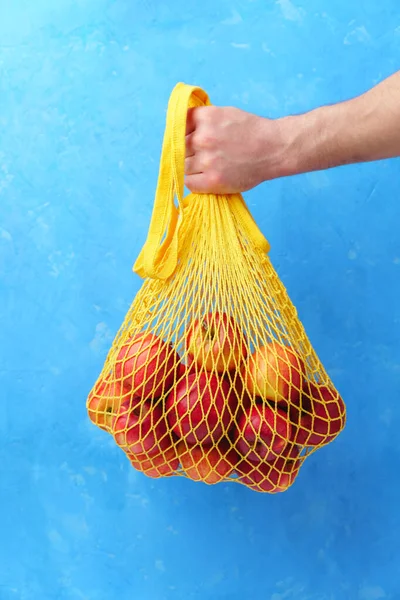 Mão masculina segura um saco de cordas com maçãs vermelhas . — Fotografia de Stock