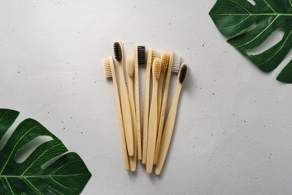 Several bamboo toothbrushes on a light concrete background. Top view with copy space. — Stock Photo, Image