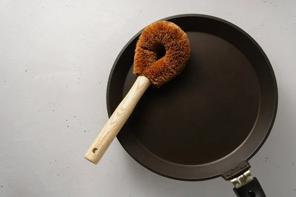 A brush made of coconut flakes with a bamboo handle over the pan. — Stock Fotó