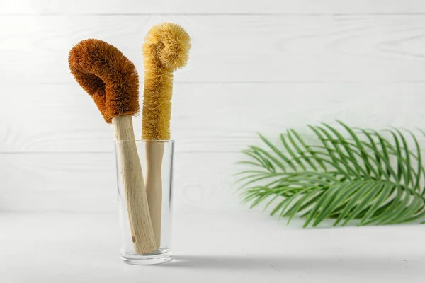 Two scrapers made of coconut bristles and a bamboo handle in a glass cup. — Stock Photo, Image