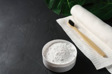 Bambu diş fırçası, diş tozu ve siyah beton arka planda beyaz pamuk havlu..
