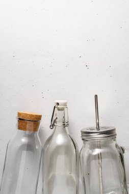 Açık gri beton arka planda üç cam şişe..