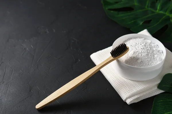 Бамбукова зубна щітка, порошок зуба та білий бавовняний рушник на чорному бетонному фоні . — стокове фото