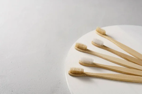 Cepillos de dientes de bambú ecológicos sobre un fondo gris claro . — Foto de Stock