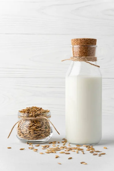 Oat milk in a bottle and grains in a glass jar. Shot in high key.