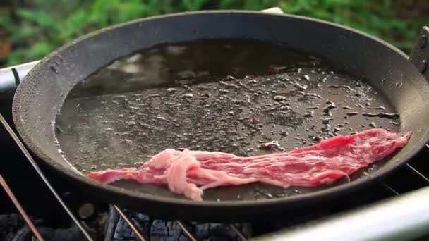 Placera råa skivor bacon i en varm skillet med tång. — Stockvideo