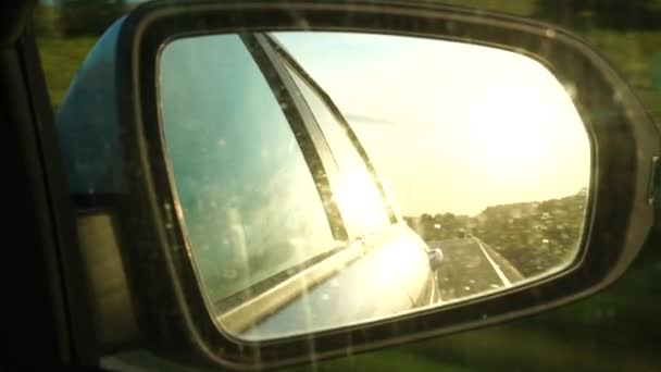 Reflektion av sommarsolnedgång och väg i backspegeln på bilen — Stockvideo