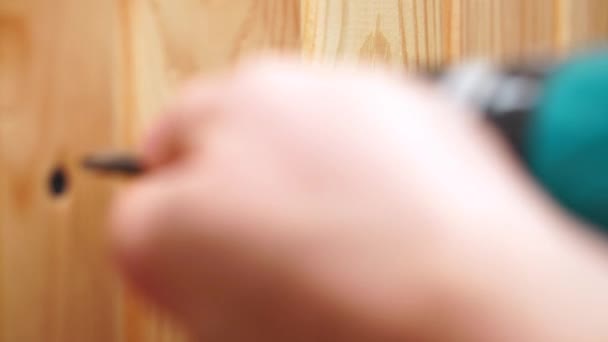 Primer plano de las manos masculinas desenroscar tornillos de estructuras de madera utilizando un destornillador inalámbrico . — Vídeos de Stock