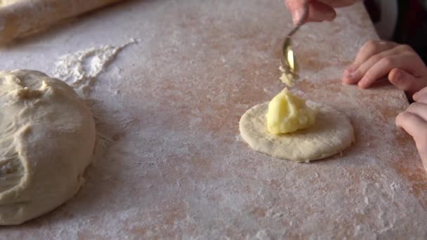 A little granddaughter helps her grandmother sculpt pies with potato filling. — Stock videók