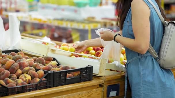 Una joven compra fruta en un supermercado . — Vídeo de stock