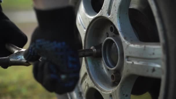 Detailní záběr mužských rukou odšroubuje šrouby kola pomocí klíče. — Stock video