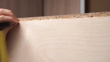 Genç bir adamın çekiçle kontrplağa çivi çakması..