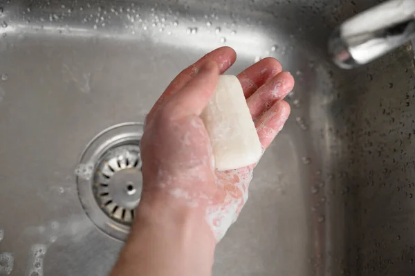 Коронавирусная инфекция защиты, человек моет руки с мылом над стальной раковиной — стоковое фото