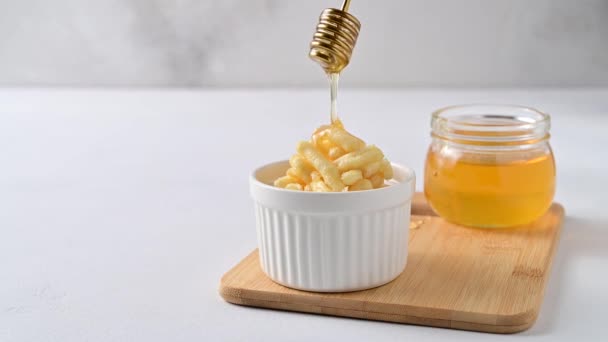 Honey is pouring from a honey dipper onto a chuck chuck. — Stock Video