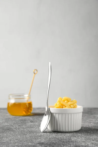 Dessert sucré composé de pâte et de chak-chak au miel dans un bol blanc en céramique et une cuillère à café sur une table en béton gris . — Photo