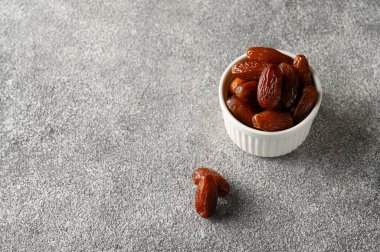 Gri beton arka planda beyaz bir kasede meyvelerle buluşur..