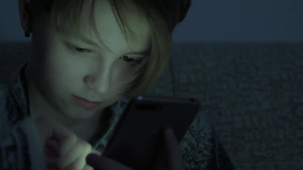 Дівчина-підліток використовує смартфон у темній кімнаті . — стокове відео