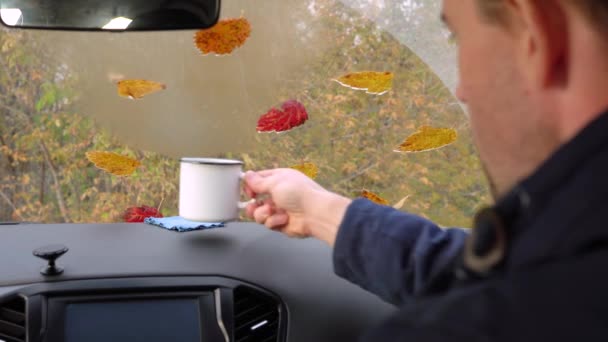 Un hombre adulto se sienta dentro de un coche, bebiendo té de la taza . — Vídeos de Stock
