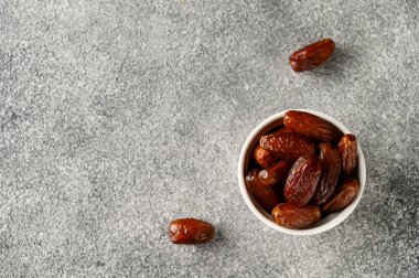 Gri beton arka planda beyaz bir kasede meyvelerle buluşur..