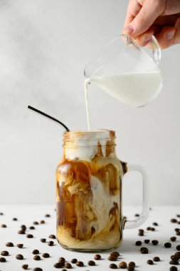 Süt, arka plandaki buzlu kahve kavanozuna dökülür..