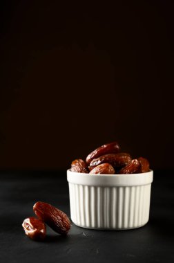 Arka planda beyaz bir kasede meyveler..