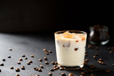 Siyah beton bir masada, cam bir fincanda buzlu kahve..