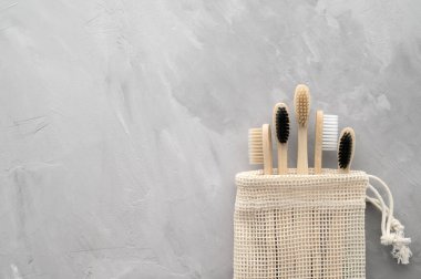 Sıfır atık. Pamuk bir çantada, gri beton bir arka planda, doğa üstü bambu diş fırçaları..