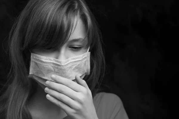 Dark black and white image of a teenager girl in a protective mask coughing, surrounded by smoke. — Stock Photo, Image