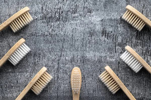 Concepto de cero residuos. Conjunto de cepillos de dientes de bambú ecológicos sobre un fondo de madera gris . — Foto de Stock